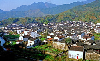 阳光下连绵的青山和错落有致的乡村建筑风光